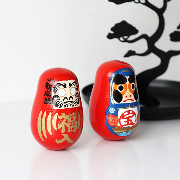 「起き上がり小法師」（七転八起の縁起物）と海外の「 Roly Poly」（倒れても起きる玩具）をミックス。