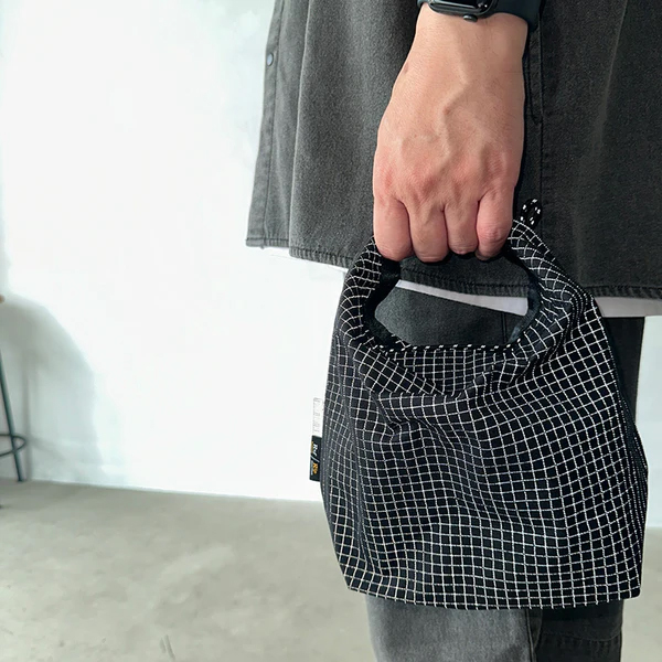 格子柄部分に反射糸を使った素材を使用したロールトップバッグ。