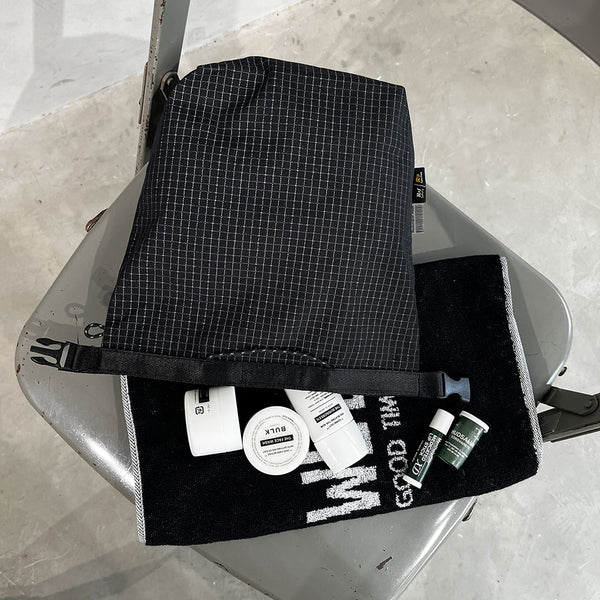 格子柄部分に反射糸を使った素材を使用したロールトップバッグ。