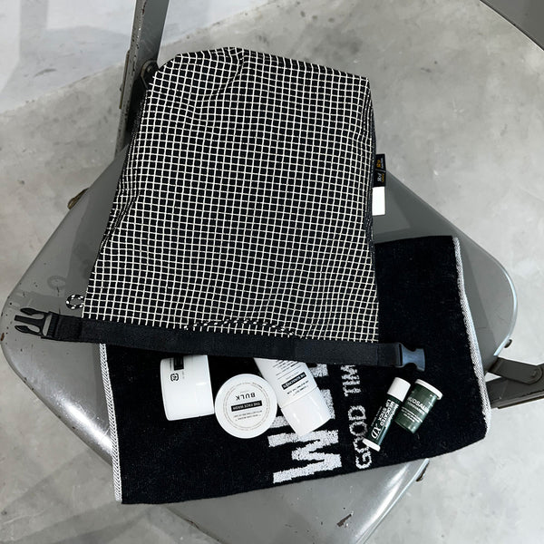 格子柄部分に反射糸を使った素材を使用したロールトップバッグ。