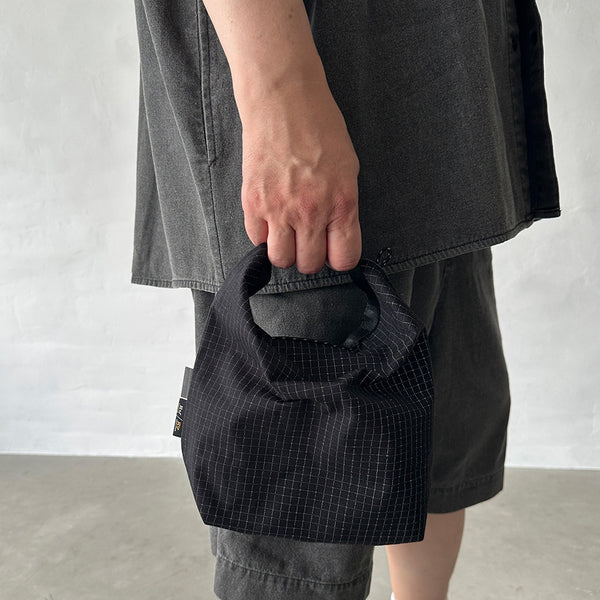 格子柄部分に反射糸を使った素材を使用したロールトップバッグ。