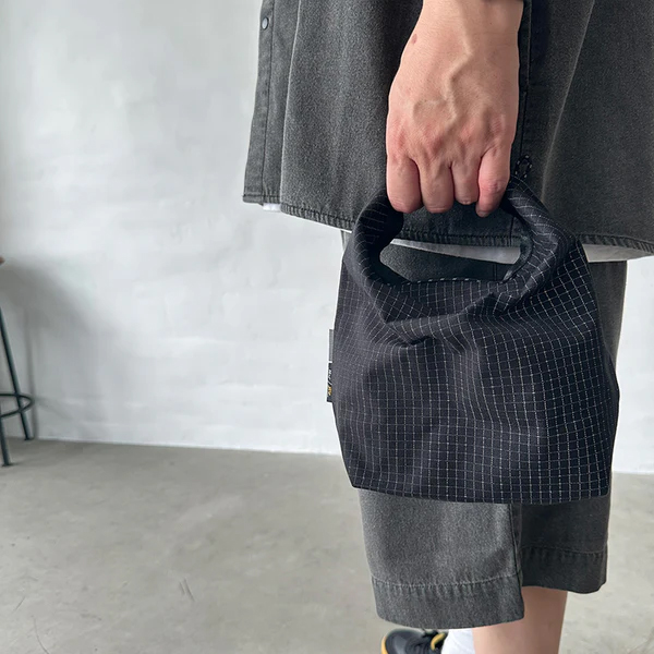 格子柄部分に反射糸を使った素材を使用したロールトップバッグ。