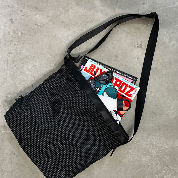 格子柄部分に反射糸を使った素材を使用したショルダーバッグ。