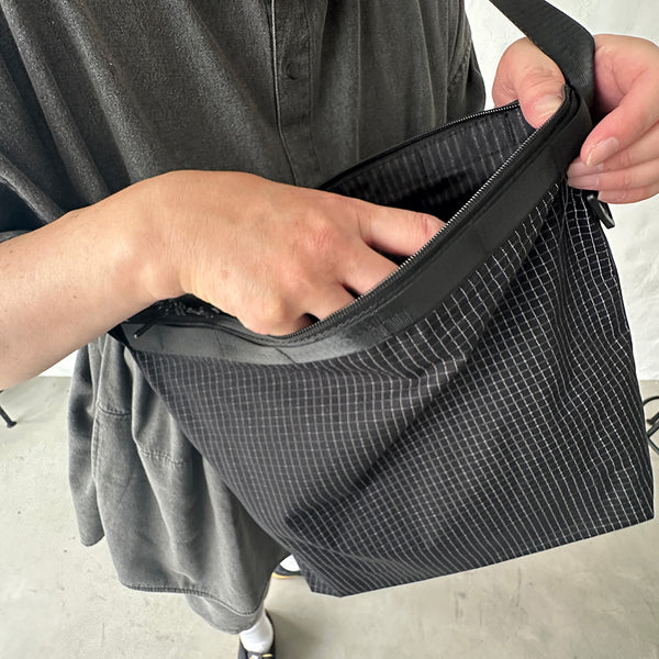 格子柄部分に反射糸を使った素材を使用したショルダーバッグ。